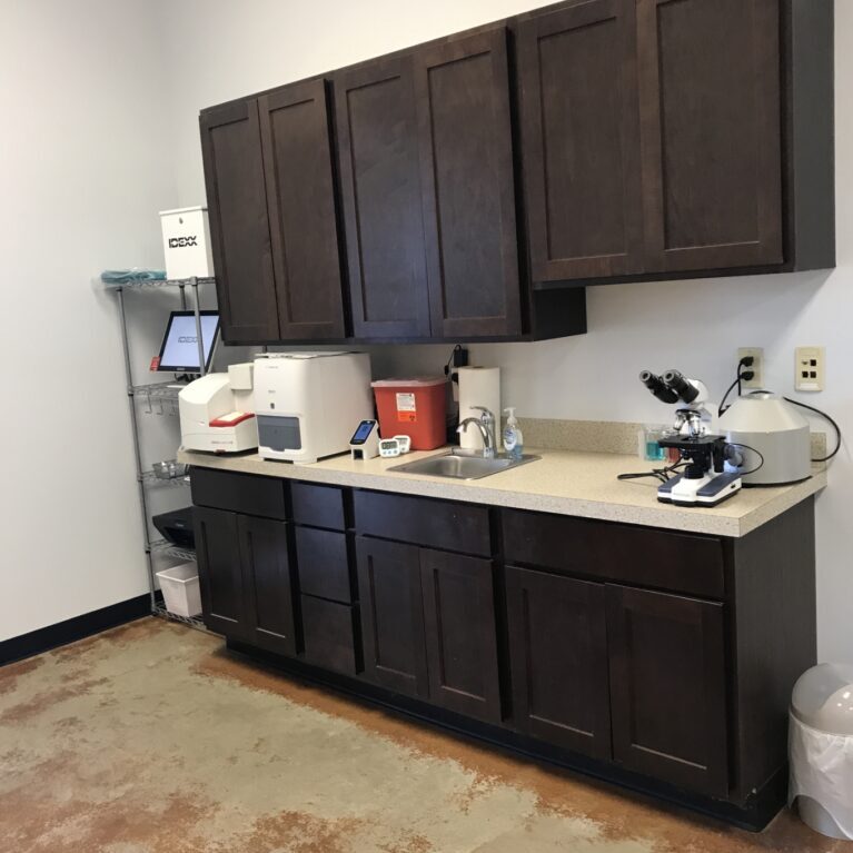 A wall of dark cabinet and beige counter with medical supplies on top of the counter